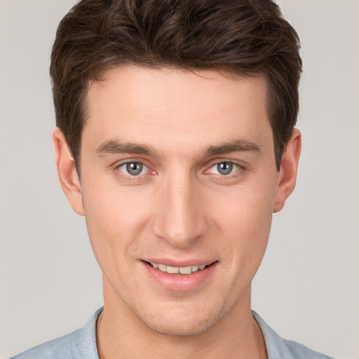 Joyful white young-adult male with short  brown hair and grey eyes