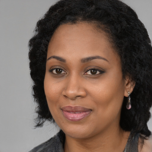 Joyful black young-adult female with long  black hair and brown eyes