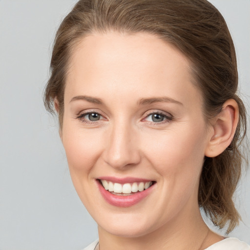 Joyful white young-adult female with medium  brown hair and grey eyes