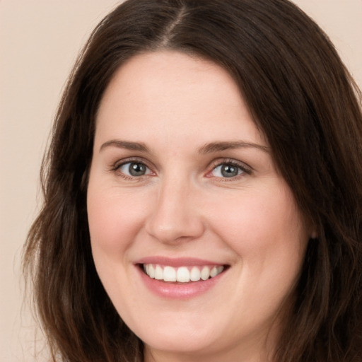 Joyful white young-adult female with long  brown hair and brown eyes