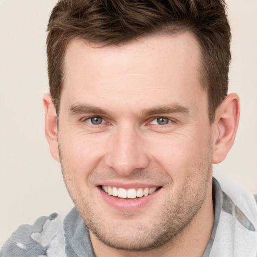 Joyful white young-adult male with short  brown hair and grey eyes