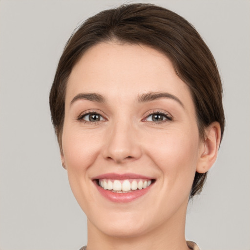 Joyful white young-adult female with medium  brown hair and green eyes