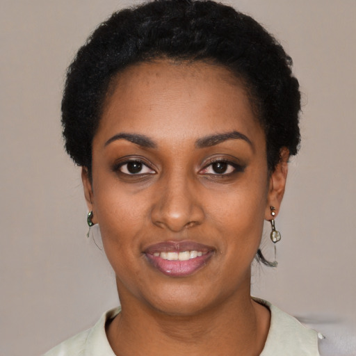 Joyful black young-adult female with short  black hair and brown eyes