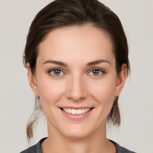 Joyful white young-adult female with medium  brown hair and grey eyes