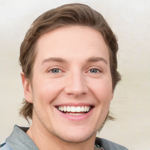 Joyful white young-adult male with short  brown hair and blue eyes