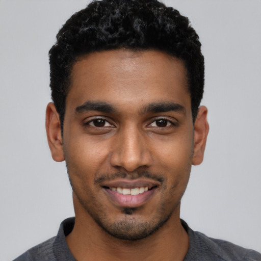 Joyful black young-adult male with short  black hair and brown eyes