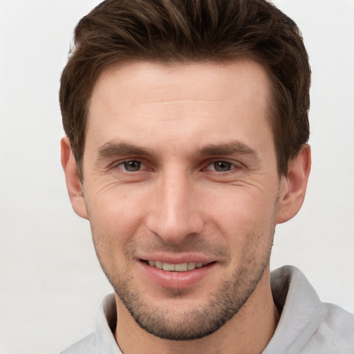 Joyful white young-adult male with short  brown hair and grey eyes