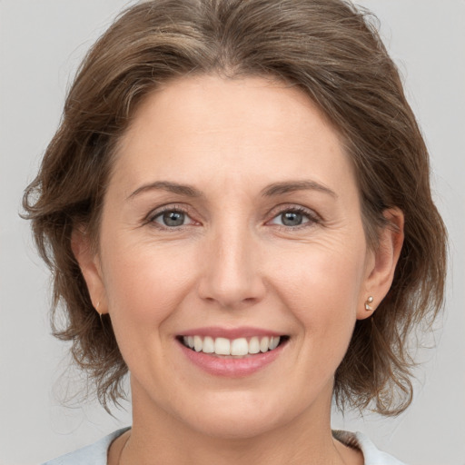 Joyful white adult female with medium  brown hair and grey eyes