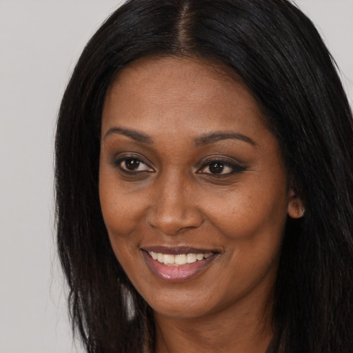 Joyful black young-adult female with long  black hair and brown eyes