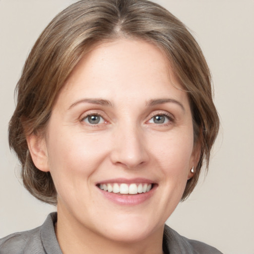 Joyful white young-adult female with medium  brown hair and grey eyes