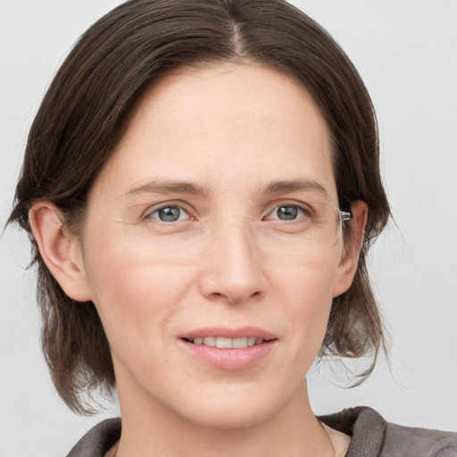 Joyful white young-adult female with medium  brown hair and grey eyes