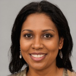 Joyful black young-adult female with long  brown hair and brown eyes