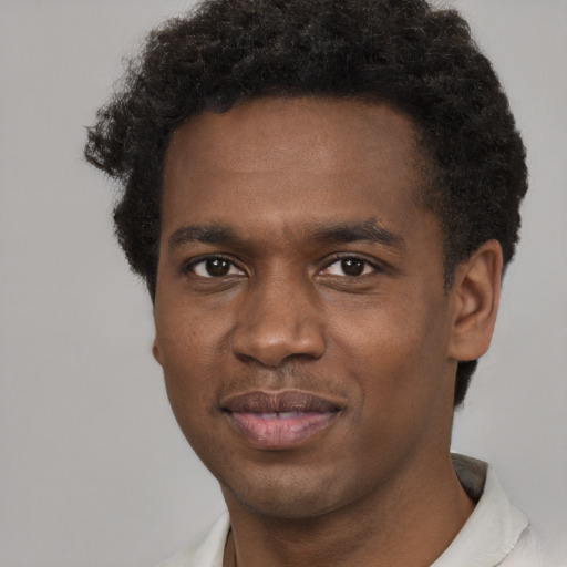 Joyful black young-adult male with short  black hair and brown eyes