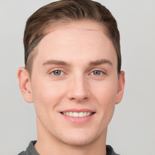 Joyful white young-adult male with short  brown hair and grey eyes