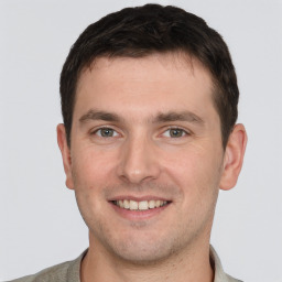 Joyful white young-adult male with short  brown hair and grey eyes