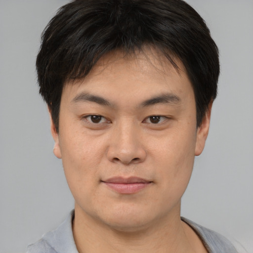 Joyful asian young-adult male with short  brown hair and brown eyes
