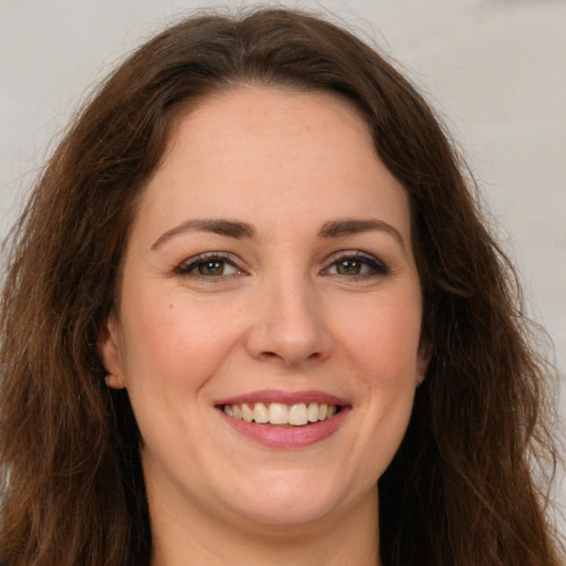 Joyful white adult female with long  brown hair and green eyes