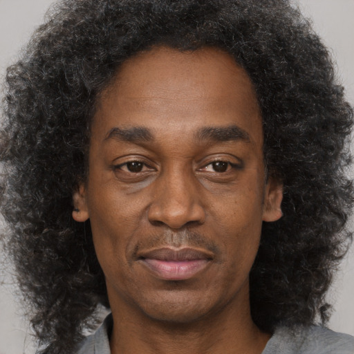 Joyful black adult male with long  brown hair and brown eyes
