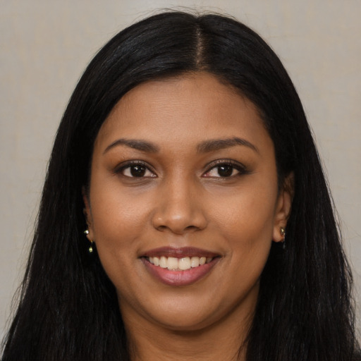 Joyful black young-adult female with long  black hair and brown eyes