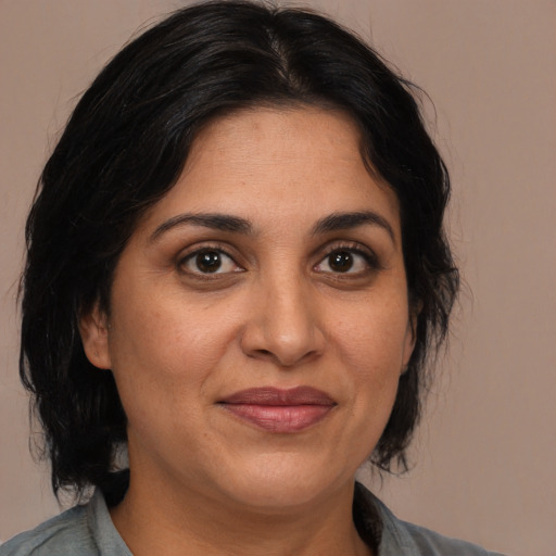 Joyful latino adult female with medium  brown hair and brown eyes