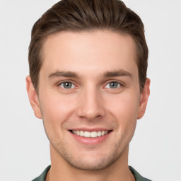 Joyful white young-adult male with short  brown hair and grey eyes