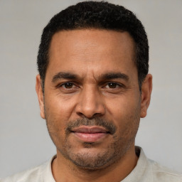 Joyful latino adult male with short  black hair and brown eyes