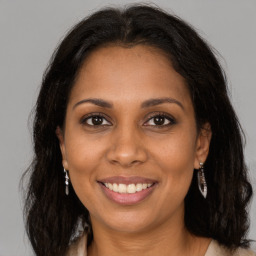 Joyful black young-adult female with long  brown hair and brown eyes