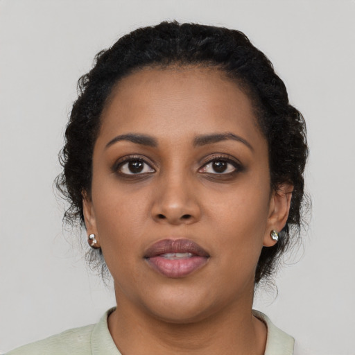 Joyful black young-adult female with short  black hair and brown eyes