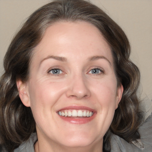 Joyful white adult female with medium  brown hair and blue eyes