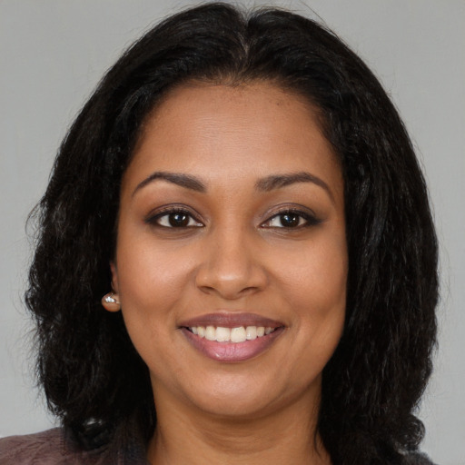 Joyful black young-adult female with long  brown hair and brown eyes