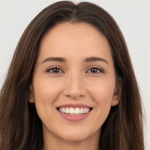 Joyful white young-adult female with long  brown hair and brown eyes