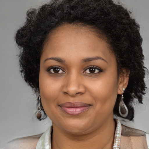 Joyful black young-adult female with long  brown hair and brown eyes