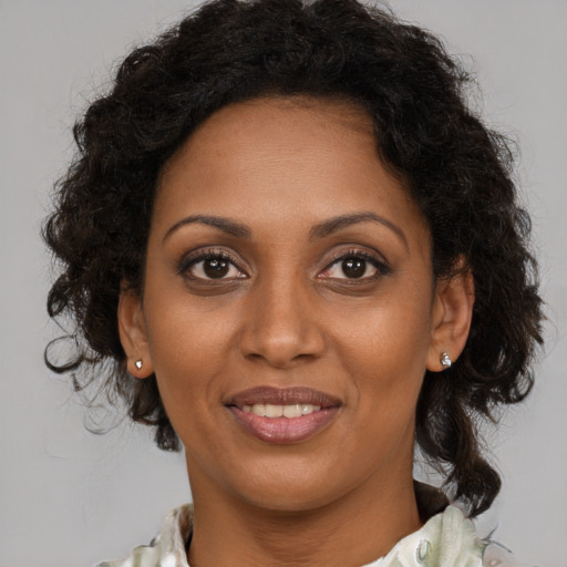 Joyful black adult female with long  brown hair and brown eyes