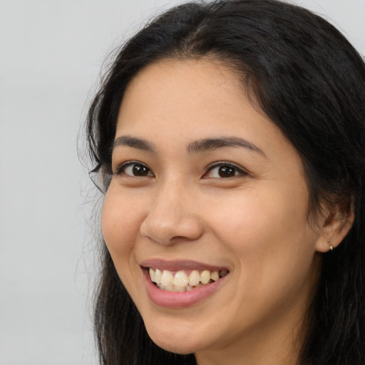 Joyful latino young-adult female with long  brown hair and brown eyes