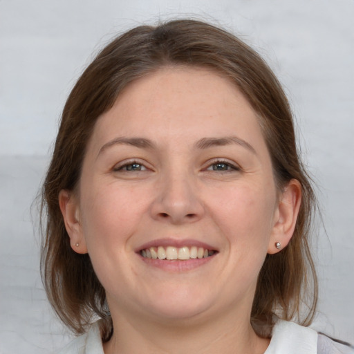 Joyful white young-adult female with medium  brown hair and grey eyes