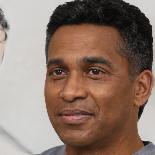 Joyful black adult male with short  black hair and brown eyes