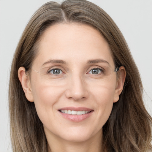 Joyful white adult female with long  brown hair and grey eyes