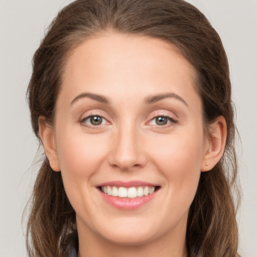 Joyful white young-adult female with long  brown hair and green eyes