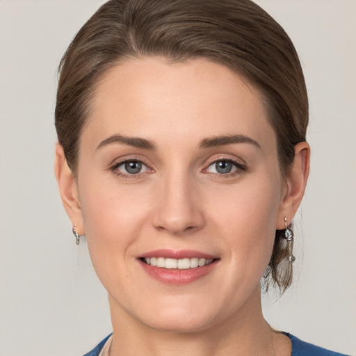 Joyful white young-adult female with medium  brown hair and grey eyes