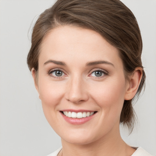 Joyful white young-adult female with medium  brown hair and grey eyes