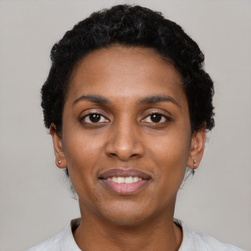 Joyful black young-adult female with short  black hair and brown eyes