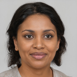 Joyful black adult female with medium  brown hair and brown eyes