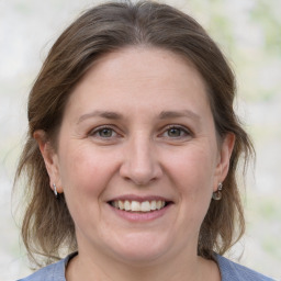 Joyful white adult female with medium  brown hair and grey eyes