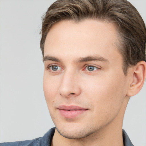 Joyful white young-adult male with short  brown hair and grey eyes