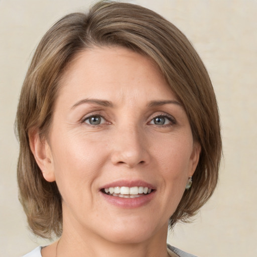 Joyful white adult female with medium  brown hair and green eyes