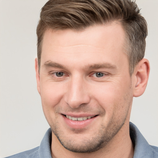 Joyful white young-adult male with short  brown hair and grey eyes