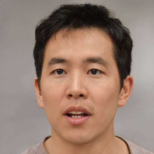 Joyful asian young-adult male with short  brown hair and brown eyes