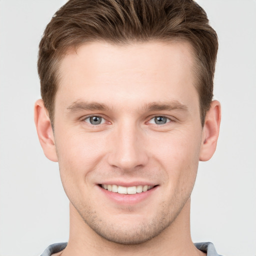 Joyful white young-adult male with short  brown hair and grey eyes