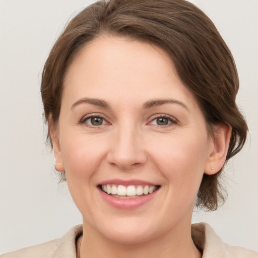 Joyful white young-adult female with medium  brown hair and grey eyes