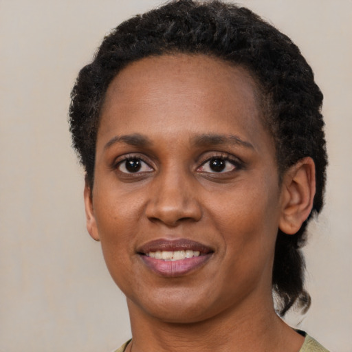 Joyful black young-adult female with short  black hair and brown eyes